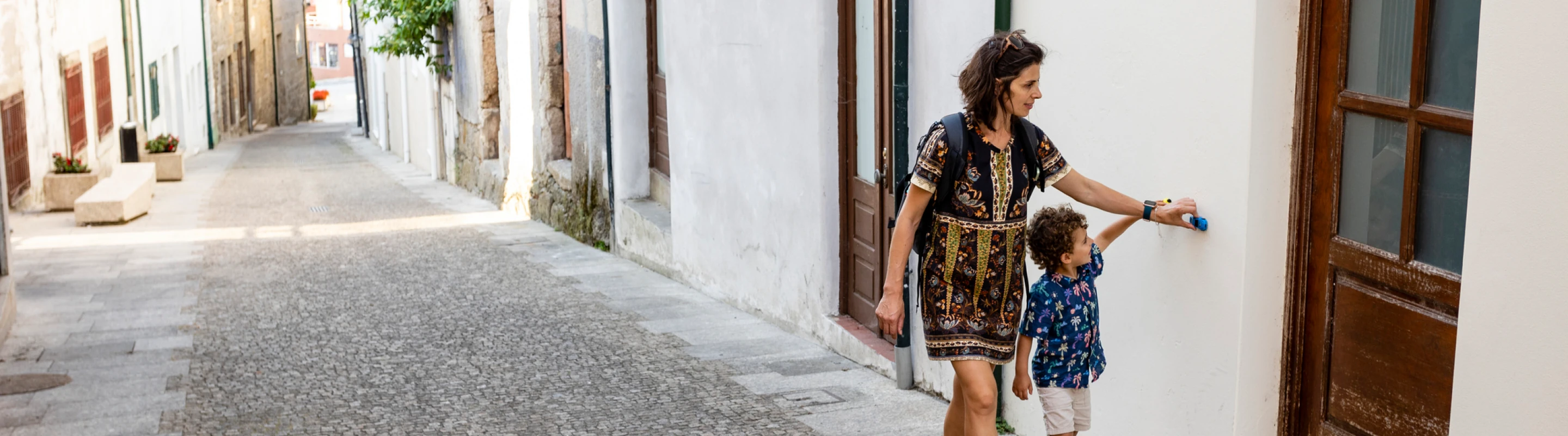 Mother with travel insurance for Portugal walking with her son on a cobblestone street in Arcos de Valdevez