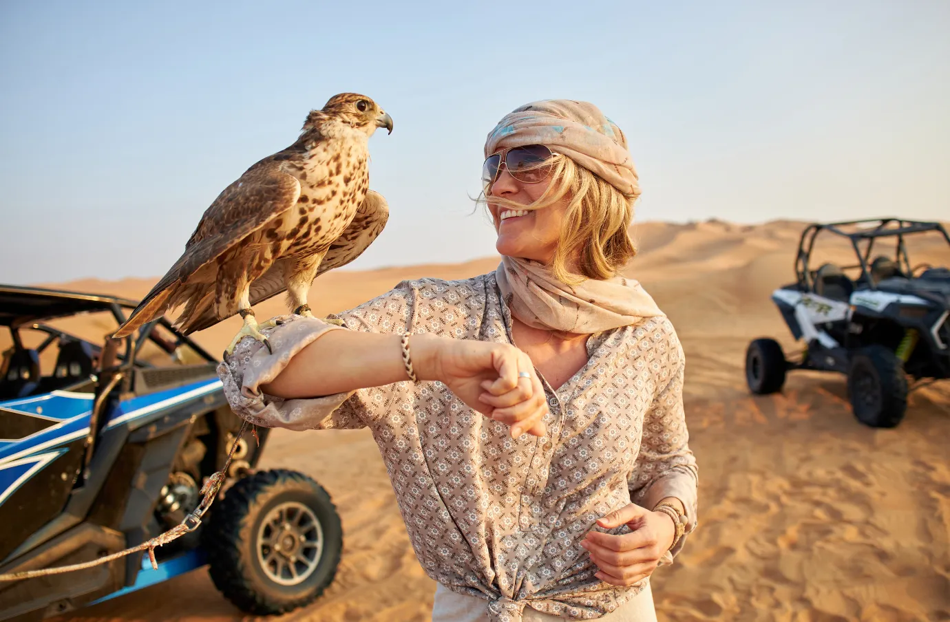 a woman with travel insurance for Dubai participates in a falconry experience during a desert safari in the UAE