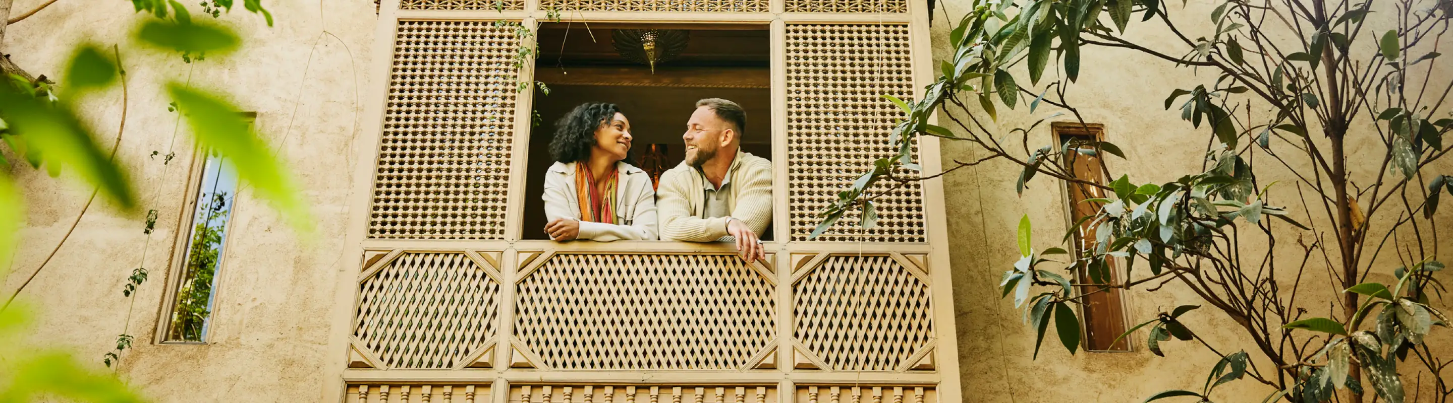 Couple with travel insurance plans smiling at each other on a balcony in Morocco