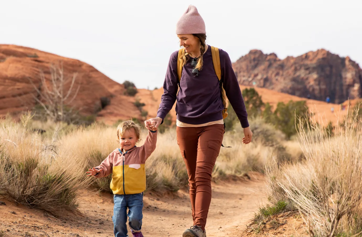 Mother holds hands with her toddler son and walks in the desert after comparing travel insurance plans 