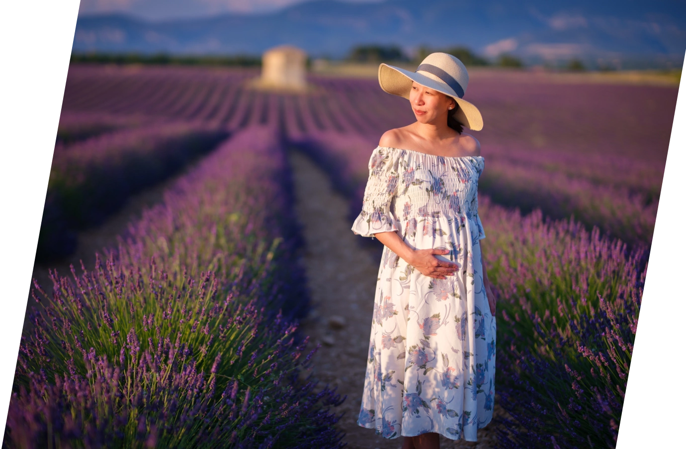 a woman wearing a floral dress walks through lavender fields in Provence, insured with travel insurance for pregnancy