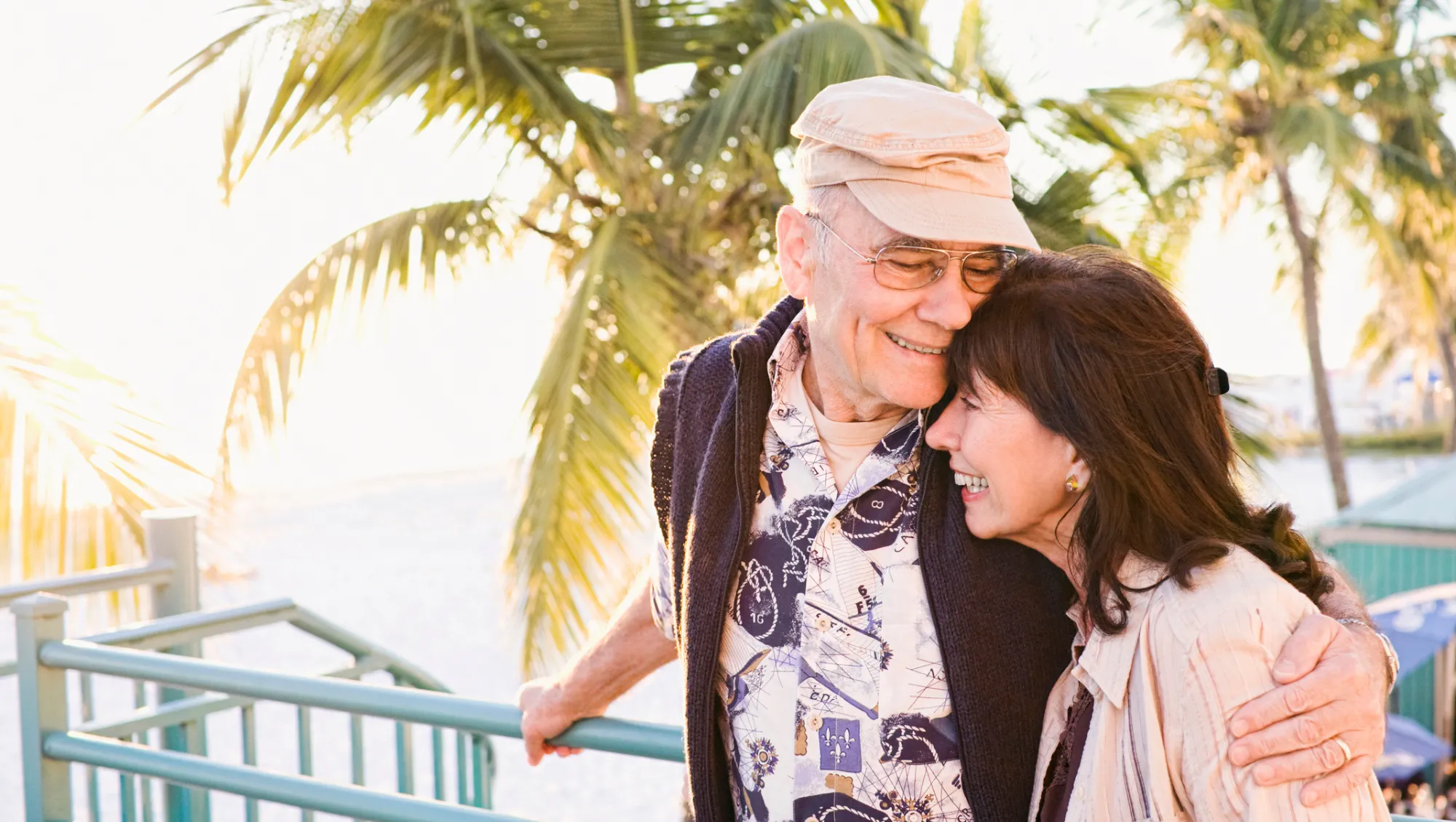a senior couple embraces at a beach resort after questioning, "Is travel insurance worth it?"